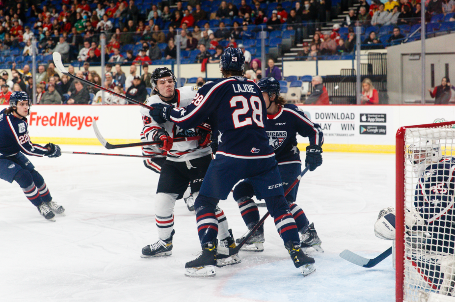 Marc Lajoie of the Tri-City Americans holds back James Stefan of the Portland Winterhawks in front of the Americans net.