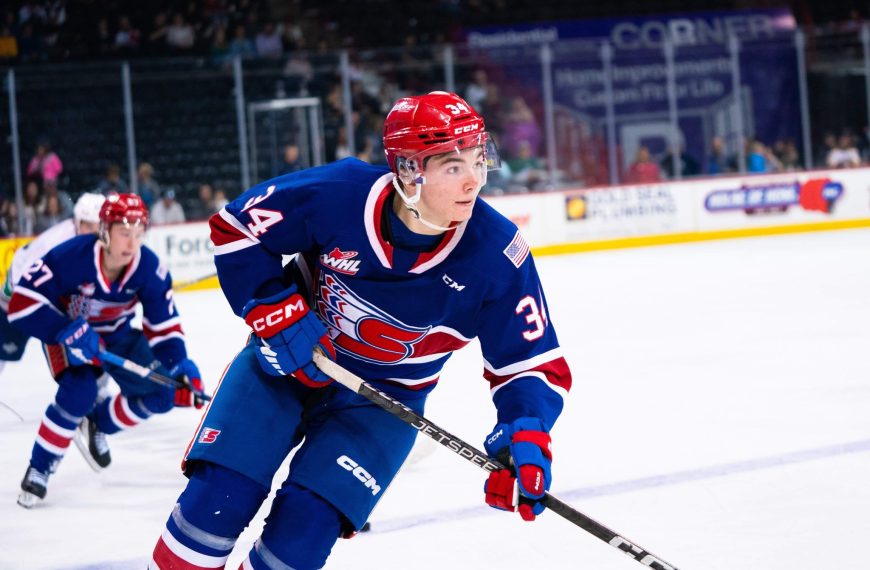An action shot of Conner Roulette on the ice in the blue Chiefs uniform. He's skating, holding his stick, looking to the right.
