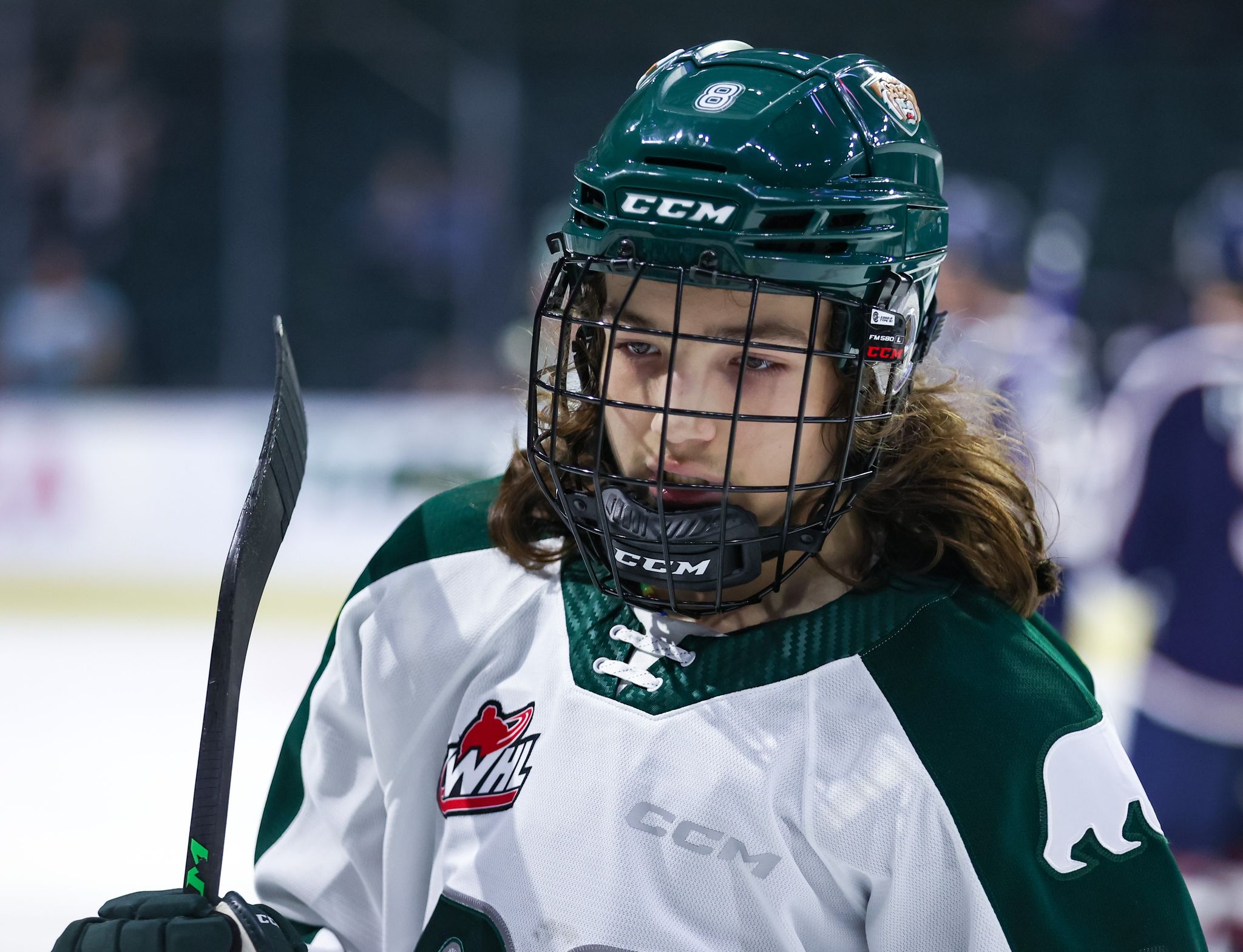 Silvertips player Ethan Makokis in the white jersey. He has a green helmet on and a black face cage on.