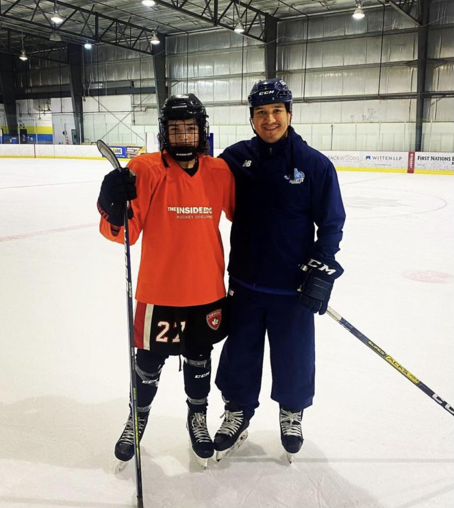 Ethan Makokis poses for a picture with Wacey Rabbit on the ice.